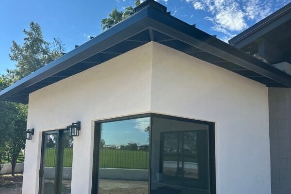 Modern white house exterior featuring large windows and a stylish roof against a blue sky. Ideal for home design inspiration.