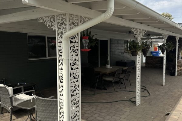Patio with decorative white columns, a gutter system, and a hummingbird feeder under a cloudy sky. Ideal outdoor space.